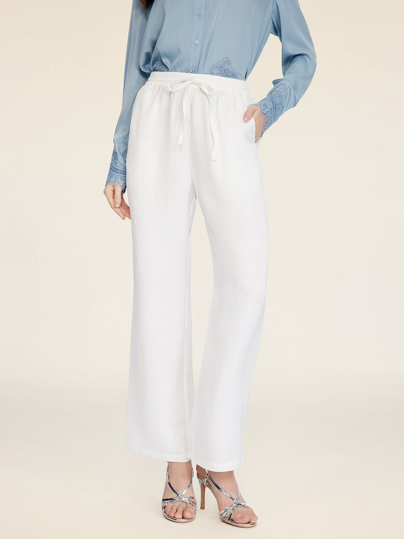 A person wearing Social Queen's Linen Straight-Leg Pants stands against a plain background, paired with a light blue long-sleeve shirt and silver heeled sandals.