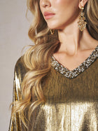 A woman with wavy blonde hair wears the Social Queen Metallic Crystal-Embellished Slit Dress and large gold earrings, her face partially visible as she looks to the side.