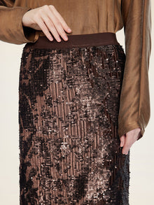 A person wears a brown long-sleeve blouse paired with the Social Queen Ombre Sequin Velvet Skirt, one hand resting on the waistband.