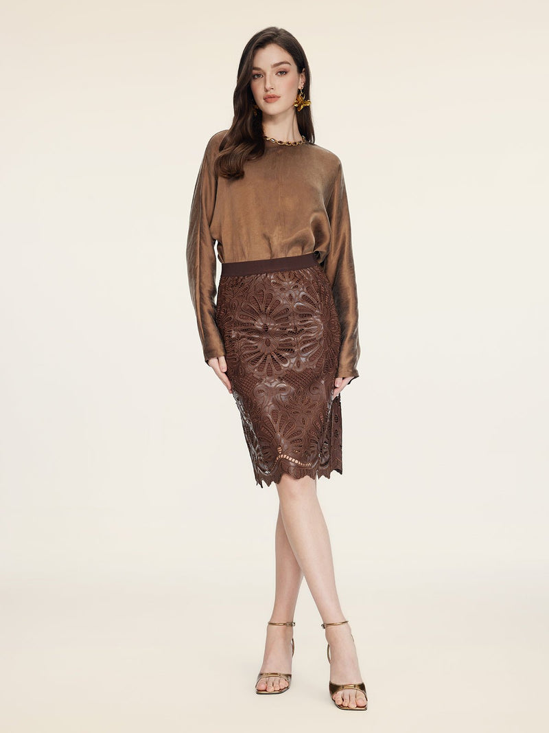 A woman stands against a plain background wearing a brown satin blouse, strappy heels, and the Social Queen Openwork Embroidered Leather Skirt.
