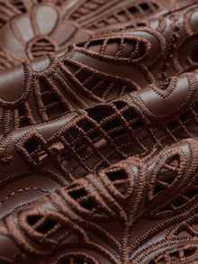 Close-up of the Social Queen Openwork Embroidered Leather Skirt, showcasing detailed hand-embroidered openwork, lace-like patterns, textured stitching, and a wavy hem.