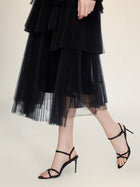 A person wearing the Social Queen Organza Pleated Skirt and black strappy high-heeled sandals walks on a light background.