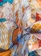 A close-up of the Social Queen Original Pattern Print Silk Scarf, featuring colorful clouds, buildings, a hot air balloon, an eye, and abstract shapes—a vibrant accessory ideal for any wedding guest.
