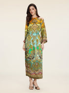 A woman stands against a plain background wearing the Social Queen Paisley Printed Silk Satin Dress, featuring vintage-inspired hand-printed paisley patterns with a blue belt and open-toe sandals.