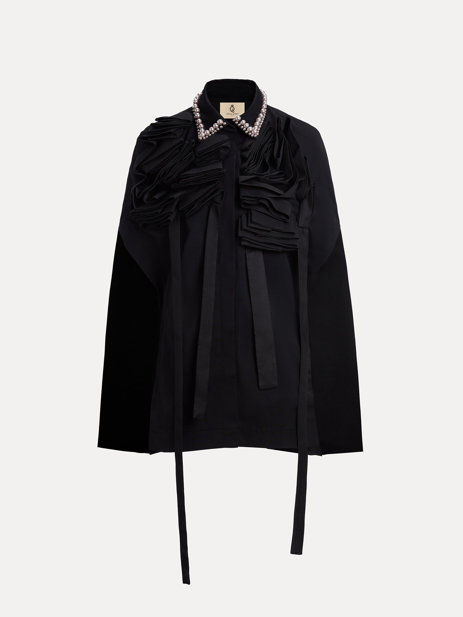 The Social Queen Pearl & 3D Floral Couture Cape features couture craftsmanship with textured ruffle detailing, long neck ties, and a pearl-embellished collar, shown against a plain white background.