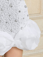 Close-up of the Social Queen Pearl-Crystal Embellished Floral Hem Mini Dress, showcasing textured white fabric, rhinestones, pearls, and large sheer ruffled hem details.