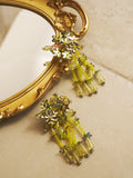 The Social Queen Petal Sequin Beaded Tassel Earrings feature handcrafted floral beads and dangling tassels, shown on a beige surface with a gold-framed mirror—an elegant choice for wedding guest jewelry.