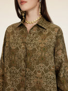 A woman wears the Social Queen Printed Linen Blouse, styled with a gold coin necklace and gold coin drop earrings; her face is partially out of frame.