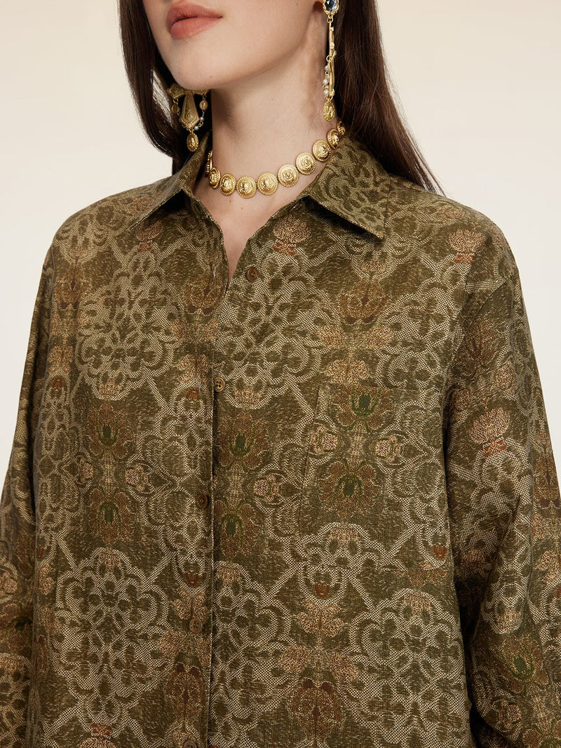 A woman wears the Social Queen Printed Linen Blouse, styled with a gold coin necklace and gold coin drop earrings; her face is partially out of frame.