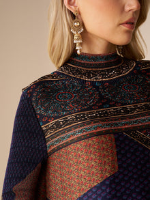 A blonde woman wears ornate gold earrings and the Social Queen Retro Ethnic Print Pleated Dress featuring a high neck, multicolored patterns, and intricate designs.
