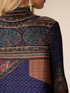 A close-up of a woman's back wearing the Social Queen Retro Ethnic Print Pleated Dress, featuring vibrant patterns and pleats, paired with a gold earring.
