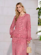 A woman wears the Social Queen Rose Appliqué 100% Mulberry Silk Blouse, featuring romantic puff sleeves and pink floral embroidery, standing indoors with a beaded handbag against white tiled walls and greenery.