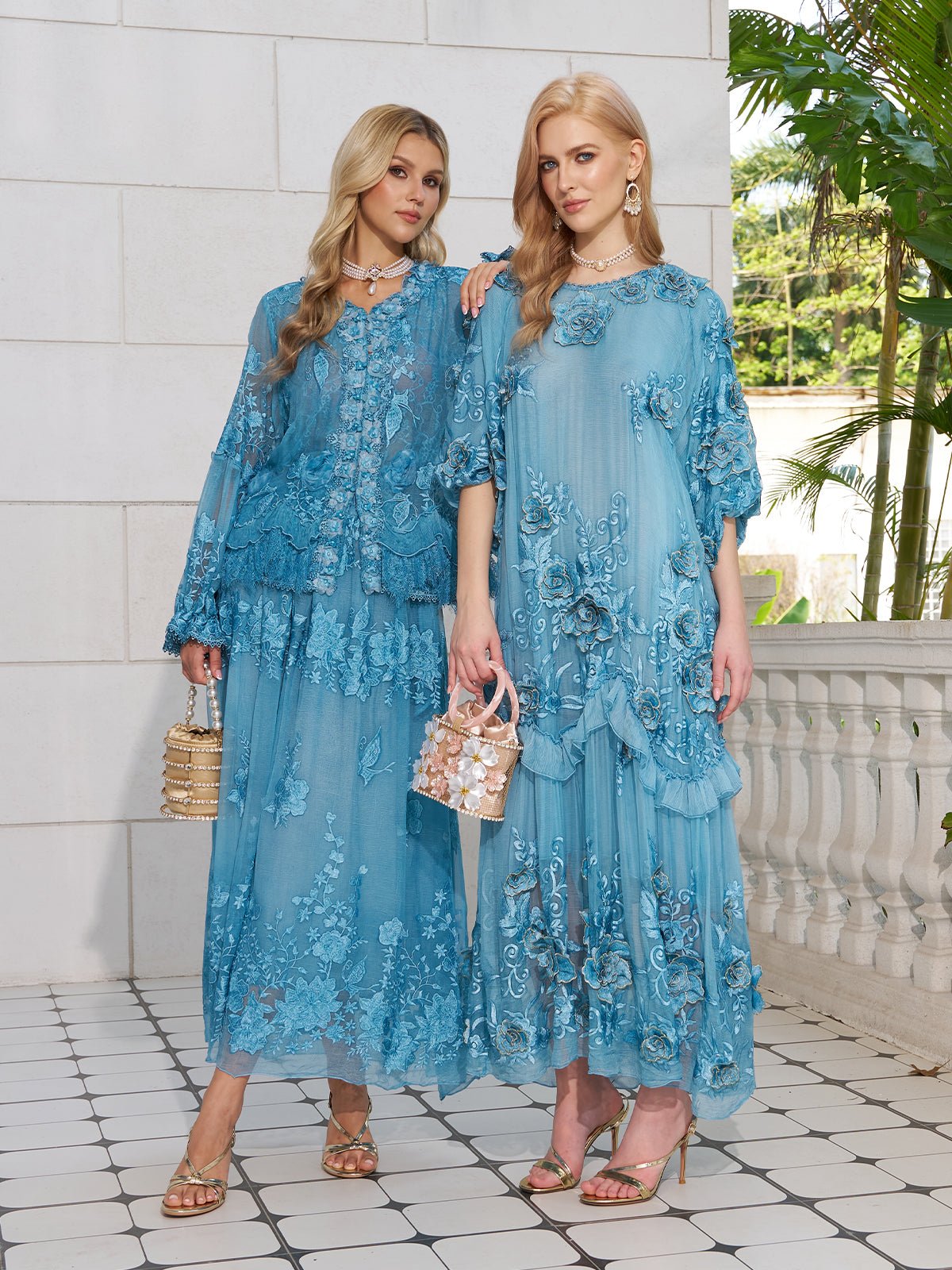 Two women wear the Social Queen Rose Appliqué 100% Mulberry Silk Dress in light blue, paired with sandals and handbags, standing on a tiled patio with white walls and greenery in the background.