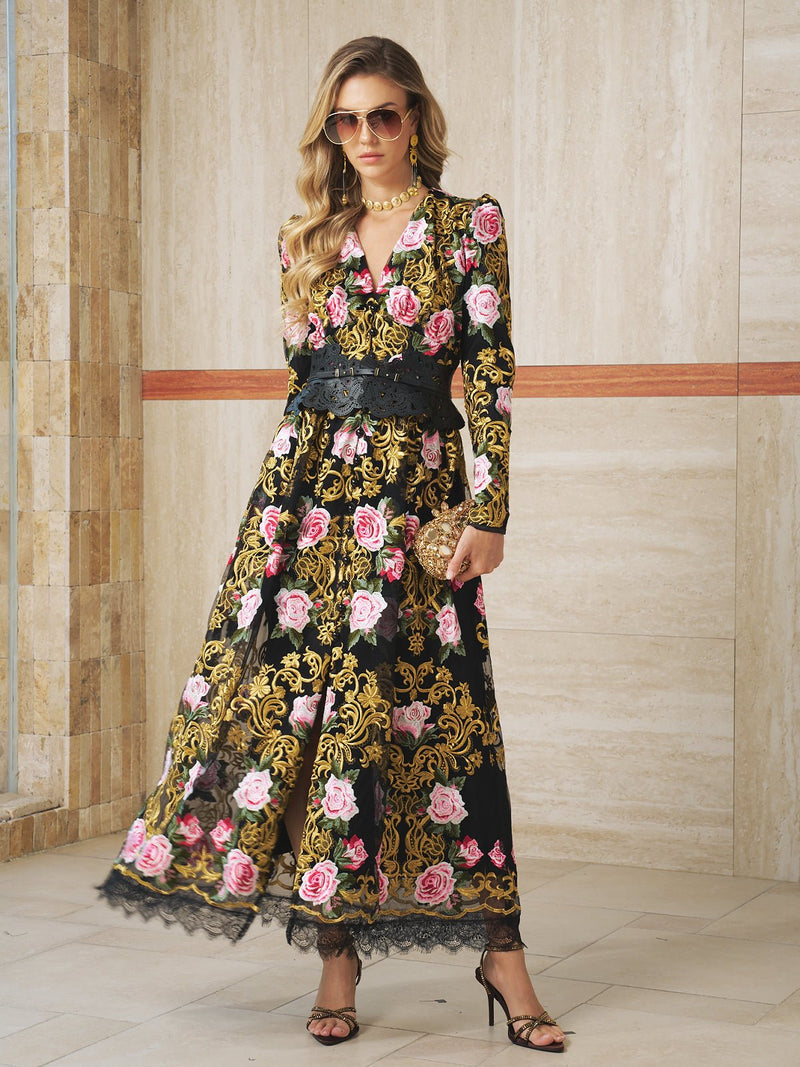 A woman in the Social Queen Rose Embroidered Lace Gown, featuring pink floral and gold Baroque accents, stands indoors by a tiled wall—an elegant choice for evening events.