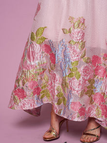 A person in the Rose Jacquard Sleeveless Gown by Social Queen, featuring a metallic sheen and crystal trim, paired with gold strappy high heel sandals, stands against a pink background.