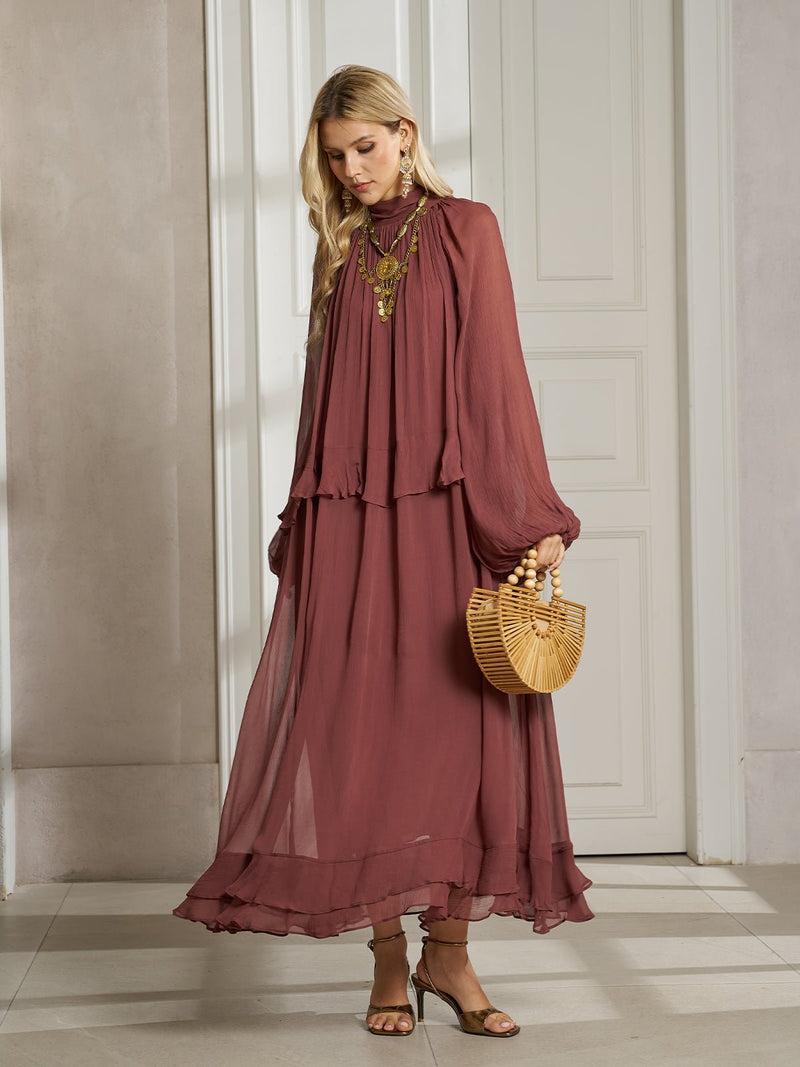 Indoors, a woman wears the Social Queen Ruched High-Neck Ruffled Midi Dress with lantern sleeves, layered necklaces, heeled sandals, and carries a wooden handbag.