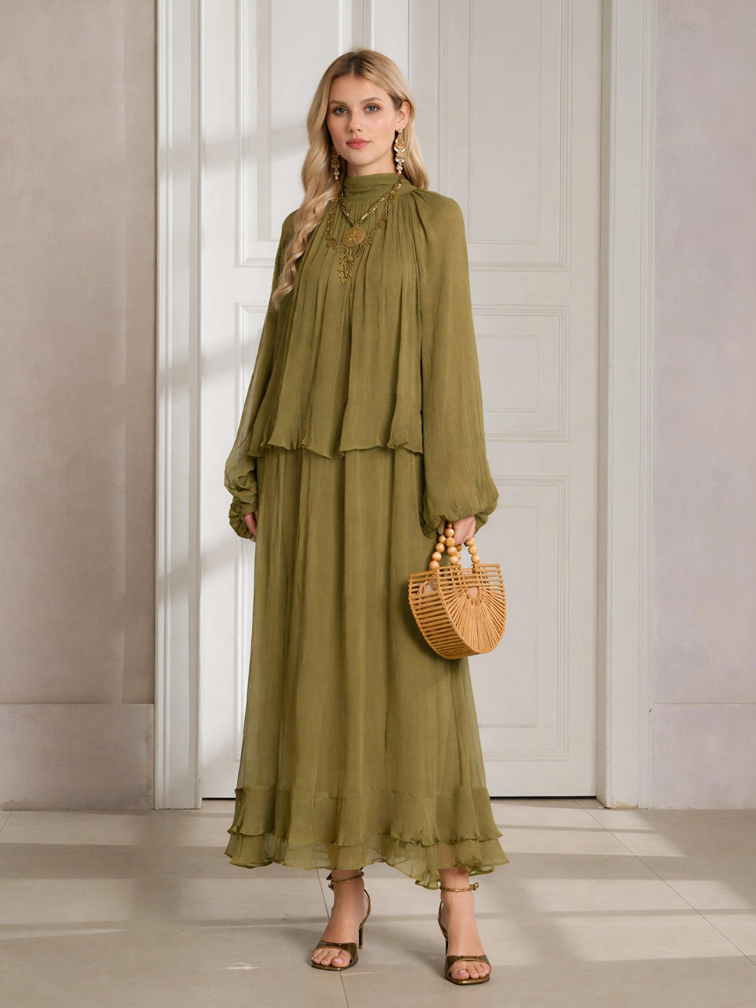 A woman stands indoors in the Social Queen Ruched High-Neck Ruffled Midi Dress—an olive green, pleated design with lantern sleeves—paired with a woven handbag and heeled sandals.