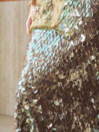 A close-up of a person wearing the Social Queen Sequin Back-Slit Midi Skirt and holding a gold clutch bag, perfect for any party celebration.