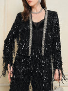 A woman styles the Social Queen Sequin & Crystal Fringe Cardigan with a black lace top, silver necklace, earrings, and diamond-trimmed accents for a versatile look.