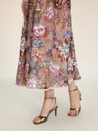 A person wears the Social Queen Sequin Embellished Floral Dress, featuring sheer fabric with floral embroidery and sequin detail, paired with gold strappy high-heeled sandals, shown from mid-calf down on a light background.