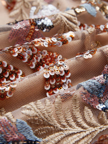 Close-up of the Sequin Embellished Floral Dress by Social Queen, featuring beige mesh fabric with floral embroidery and gold, silver, bronze, white, and blue sequins for a textured, decorative look.