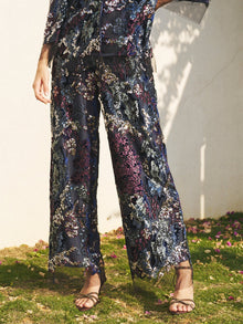 Person standing on grass wearing Social Queen Sequin Embroidered Mesh Wide-Leg Pants and a matching top with open-toe sandals. Only the lower body is visible.