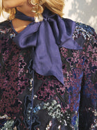Close-up of a person wearing Social Queen’s Sequin Embroidered Velvet Mesh Jacket with a large matching bow at the neck and gold earrings—ideal for a chic party celebration.