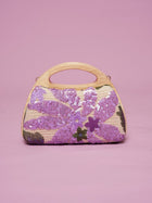 The Social Queen Sequin Embroidered Wooden Handle Bag features purple floral sequin embroidery arranged delicately on a pink background.