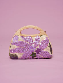 The Social Queen Sequin Embroidered Wooden Handle Bag features purple floral sequin embroidery arranged delicately on a pink background.