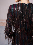A person is wearing the Social Queen Sequin Fringe Slit Evening Gown, featuring long sleeves, vertical rows of shimmering sequins, and fringe detailing.