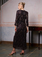 A woman wearing the Social Queen Sequin Fringe Slit Evening Gown and gold heels stands indoors with her back to the camera.