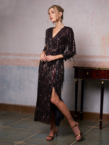 A woman wearing the Social Queen Sequin Fringe Slit Evening Gown stands indoors beside a small wooden table, looking to the side.