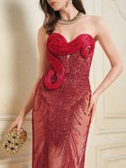 A woman in the Social Queen Sequin & Hand-Beaded 3D Pleated Tulle Gown holds a gold jeweled clutch and wears a necklace and earrings, standing against a neutral background.