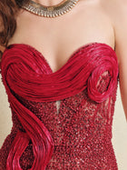 A close-up of a woman wearing the Sequin & Hand-Beaded 3D Pleated Tulle Gown by Social Queen, featuring a strapless heart neckline, intricate sequins, pleated tulle details, and accessorized with a gold necklace.