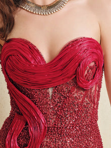 A close-up of a woman wearing the Sequin & Hand-Beaded 3D Pleated Tulle Gown by Social Queen, featuring a strapless heart neckline, intricate sequins, pleated tulle details, and accessorized with a gold necklace.