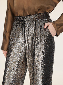 A person stands with one hand in their pocket, wearing Social Queen’s Sequin High-Waist Wide-Leg Pants and a brown satin shirt.