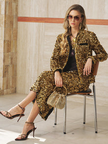 A woman in sunglasses and sandals holds a gold handbag while seated against a tiled wall, showcasing the Social Queen Sequin Velvet Skirt—ideal for adding sparkle to your next special event look.