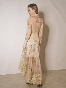 A woman stands indoors facing away from the camera, wearing the Social Queen Silk Floral Print Lace Blouse with long sleeves and a high-neck design.