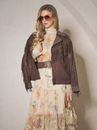 A woman wearing sunglasses, a brown fringed jacket with studs, the Social Queen Silk Floral Print Lace Blouse, and holding a gold purse poses against a light wall.