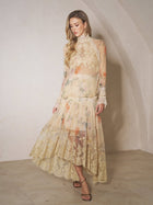 A woman stands indoors against a light-colored wall, wearing the Social Queen Silk Floral Print Lace Blouse featuring sheer panels and a high-neck design.