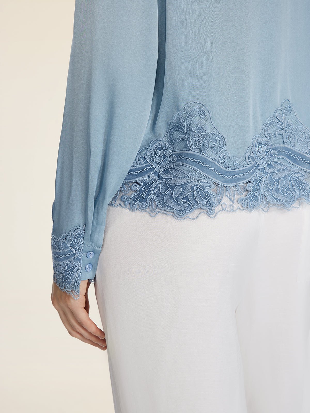 A person wearing the Social Queen Silk Satin Shirt with lace trim, paired with white pants.