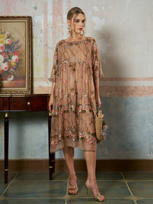 A woman stands indoors wearing the Square-Neck Embroidered Silk Dress from Social Queen, styled with gold heels and a woven handbag. A framed floral painting rests on a wooden table beside her.