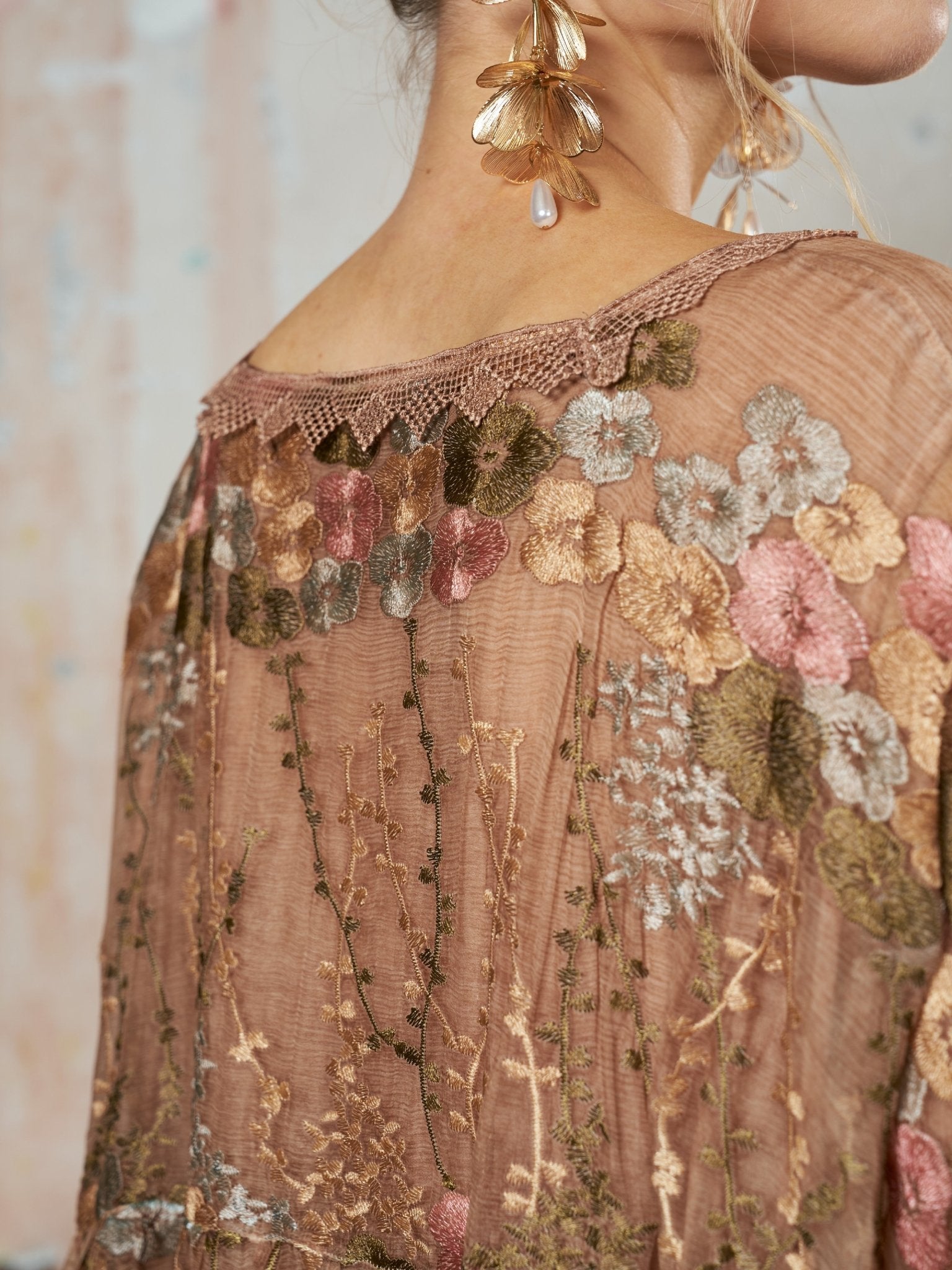 Close-up of a person wearing the Social Queen Square-Neck Embroidered Silk Dress in earthy tones, paired with gold floral earrings featuring a pearl drop.