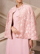 A woman wearing Social Queen’s Stand-Collar Beaded Jacquard Jacket in pale pink over a matching dress stands by a light staircase—a chic choice for a wedding guest.