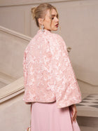 A woman stands on a staircase in a Social Queen Stand-Collar Beaded Jacquard Jacket and matching skirt, featuring light pink floral patterns—a chic choice for a wedding guest, with her hair styled in an updo.