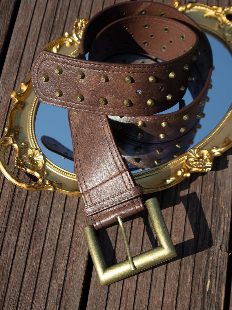 The Social Queen Studded Leather Belt is stylishly displayed on a mirror.