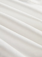 Close-up of smooth, white silk fabric with gentle folds and soft shadows, perfect for the Tie-Neck Silk Lantern Sleeve Blouse by Social Queen.