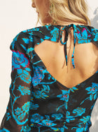 A woman is shown from behind wearing the Social Queen V-Neck Tie-Back Floral Knit Dress, a blue midi dress with pink accents and a deep V-back tied with a bow.