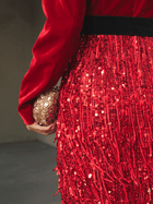 A model in the Social Queen Velvet Fringe Sequin Dress holds a small gold textured clutch in their left hand, set against a softly blurred neutral background.