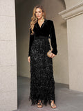 A woman poses by a stone wall in the Social Queen Velvet Fringe Sequin Dress, featuring black velvet, a tie belt, long sequin fringe skirt, gold jewelry, and a clutch—a chic choice for a wedding guest.